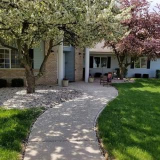 A charming front yard with a curving pathway lined by blossoming trees.