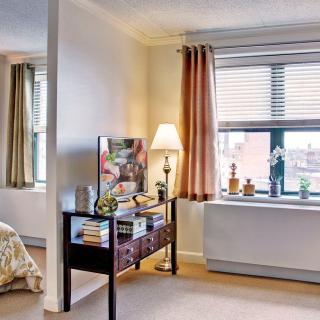 A cozy bedroom with a window view, featuring stylish furniture and decor.