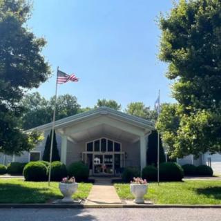 A sunny day at a building entrance with flags and trees.