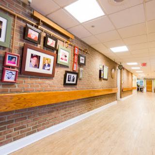 A well-lit hallway featuring a variety of framed photographs on a brick wall.