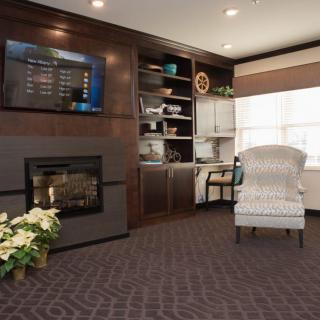 A cozy living room with a fireplace, armchair, and bookshelf.