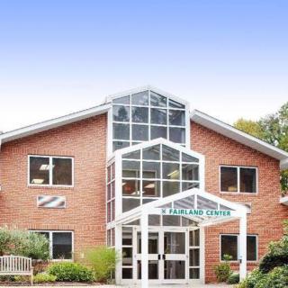 A brick building with a prominent glass entrance and multiple windows.