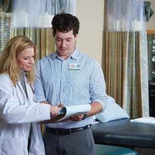 A doctor and a colleague reviewing medical documents in a healthcare setting.