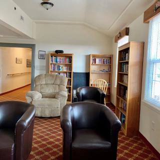A cozy library reading area featuring comfortable chairs and bookshelves filled with books.