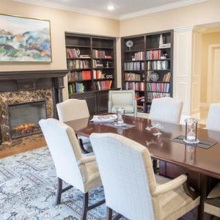 A well-appointed conference room with bookshelves, a fireplace, and seating for six.