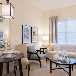 A stylish and modern living room interior featuring a cozy sofa, round glass coffee table, and elegant lighting.