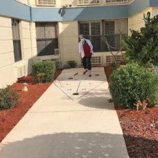 A person walking along a garden pathway outside a building.