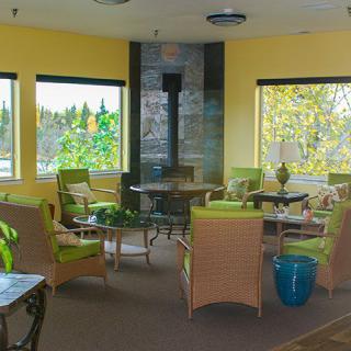 A cozy indoor lounge area with wicker furniture and large windows providing natural light.