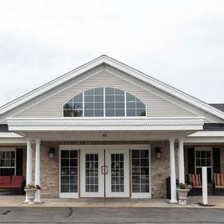 A front view of a building with a gabled roof, large windows, and double glass doors.