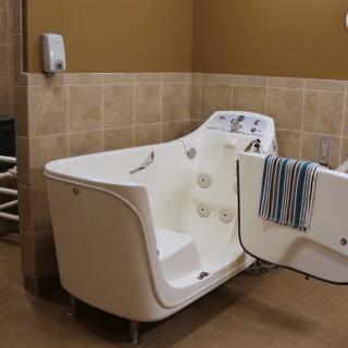 A specialized bathtub designed for hydrotherapy and accessibility, featuring a door for easy entry in a tiled bathroom setting.
