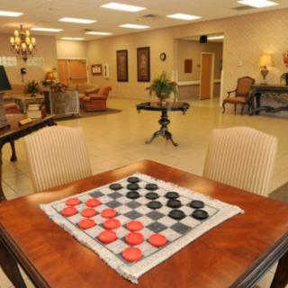 A cozy lounge with a checkers game set up on a wooden table, surrounded by comfortable seating and decor.