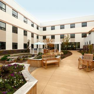 A serene courtyard featuring benches and well-maintained landscaping surrounded by a multi-story building.