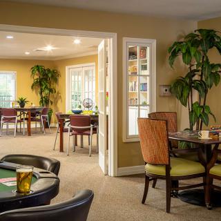 A cozy dining area with multiple tables and chairs, decorated with indoor plants.