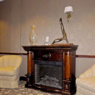 A cozy lounge area featuring an elegant fireplace with decorative sculptures and comfortable seating.
