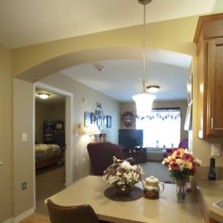 A cozy interior space featuring a kitchen and dining area overlooking a living room with floral decorations.