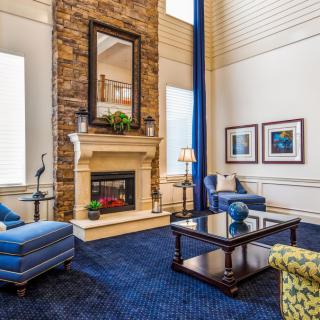 Elegant living room with a stone fireplace, blue carpet, and stylish furnishings.