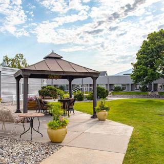 A scenic outdoor patio with a gazebo surrounded by greenery and under a partly cloudy sky.