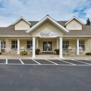A storefront building with pillars and a parking lot.