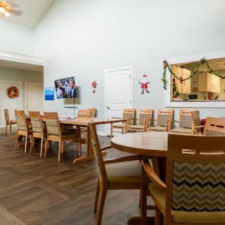 A spacious dining area featuring wooden tables and chairs, complemented by light-colored walls and minimal decorations.