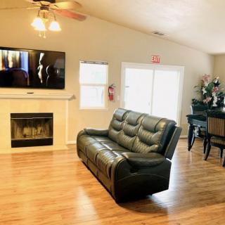 A cozy living room with a leather sofa, fireplace, mounted TV, and dining area.