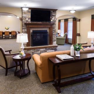 A cozy living room with a sofa and fireplace, featuring a television and warm lighting.
