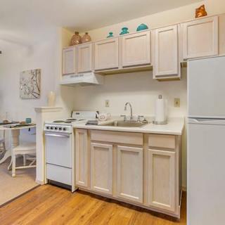 A compact kitchen area featuring light-colored cabinets, a small stove, and a refrigerator.