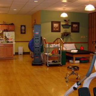 A well-lit rehabilitation therapy room equipped with exercise machines and therapy tools.