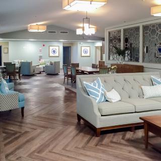 A spacious and elegantly designed living room featuring comfortable sofas, armchairs, and stylish lighting fixtures on a hardwood floor.