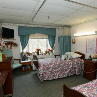A hospital room with two beds, decorated with flowers and curtains.