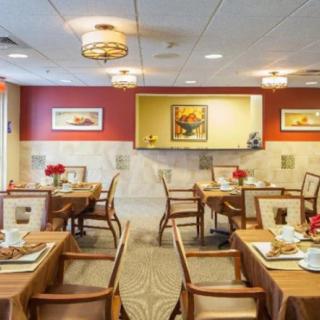 An elegantly designed restaurant dining area with neatly arranged tables and chairs, featuring warm lighting and tasteful decor.