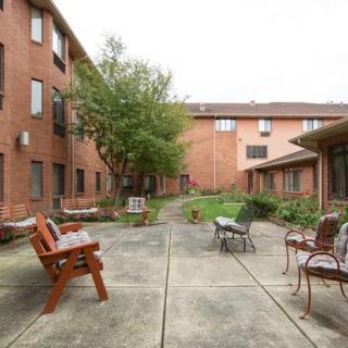 A peaceful courtyard with seating surrounded by brick buildings and greenery.