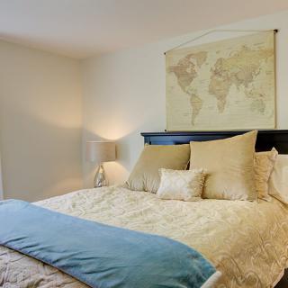 A cozy bedroom with elegant bedding and map-themed wall decor.