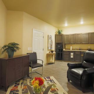 A cozy living space with an armchair, small dining table, and an open kitchen layout.