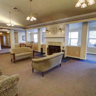 A cozy lounge area featuring sofas and a fireplace, with large windows allowing natural light to fill the room.