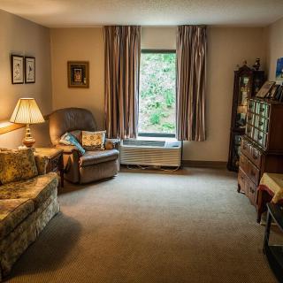 A cozy living room with comfortable seating, a soft carpet, and warm lighting.