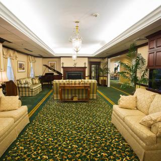 A luxurious living room featuring elegant furniture, a grand piano, and a patterned carpet.