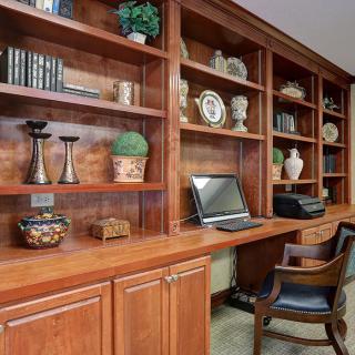 A cozy home office with wooden bookshelves filled with decorative items and a laptop on the desk.