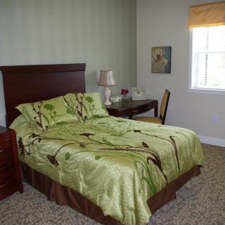 A cozy bedroom with a green-themed bedding and simple decor.