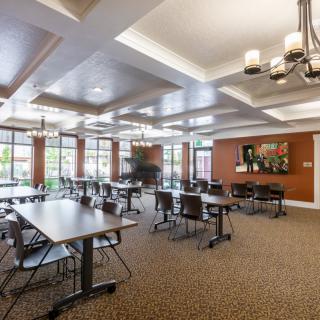 A spacious and modern meeting room with conference tables, chairs, and large windows allowing natural light.