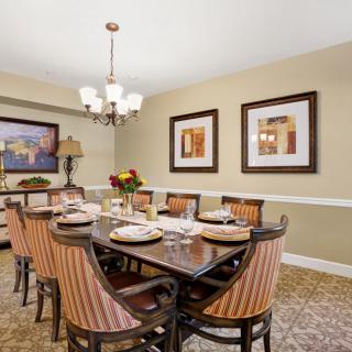 A beautifully decorated dining room with a large table, elegant chairs, artwork on the walls, and a stylish chandelier.