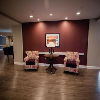 A cozy seating area with two patterned chairs and a table against a maroon accent wall.