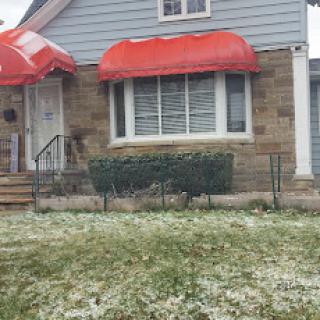 A charming house with red awnings and a grassy front yard.