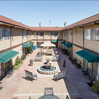 A courtyard with a central fountain, surrounded by benches and buildings with green awnings.