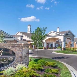 A well-maintained residential entrance with landscaped greenery and clear skies.