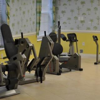 A small gym room with various exercise machines lined up against the wall.