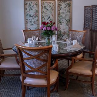 Elegant dining room setup with a flower centerpiece and decorative screen backdrop.