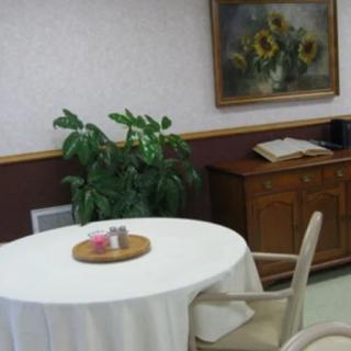 A cozy room with a round table, chairs, and decorative elements like a plant and a painting on the wall.