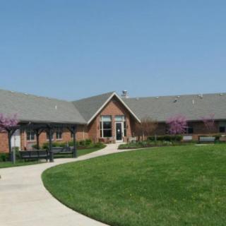 A brick building with a neatly mowed lawn and a paved pathway under a clear blue sky.