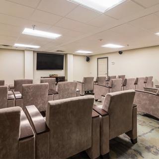 A modern conference room with multiple rows of seating and a large television.