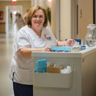 A friendly nurse smiles while attending to her duties in a hospital corridor.